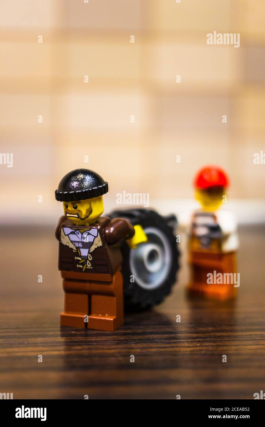POZNAN, POLAND - Dec 18, 2018: Two Lego thieves figurines moving a car wheel in soft focus back Stock Photo