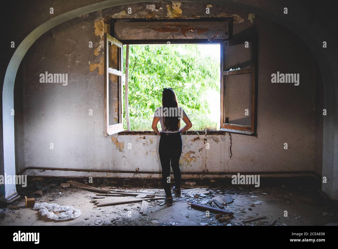 Silhouette of young Woman standing near beautiful window in old building Stock Photo