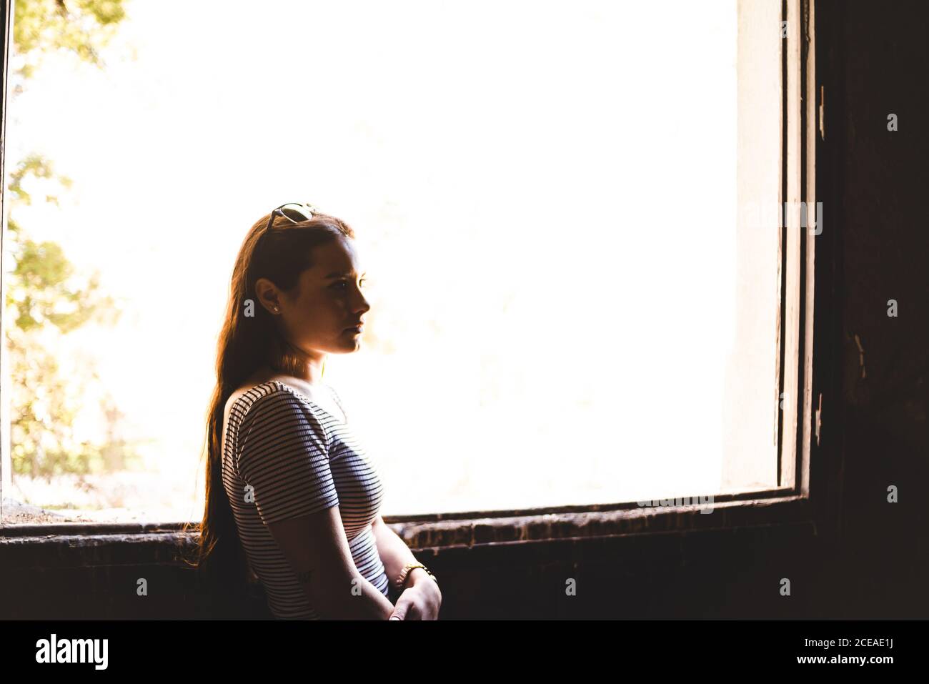 Silhouette of young Woman standing near beautiful window in old building Stock Photo