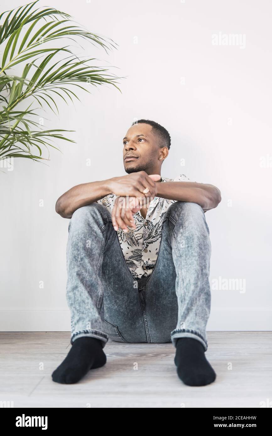 Pensive black man on ground looking away Stock Photo