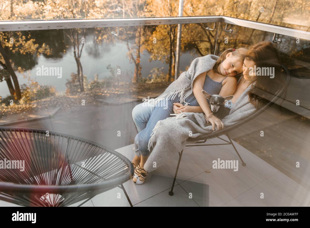 Shot through glass window of Woman with little girl and dog cuddling in ...