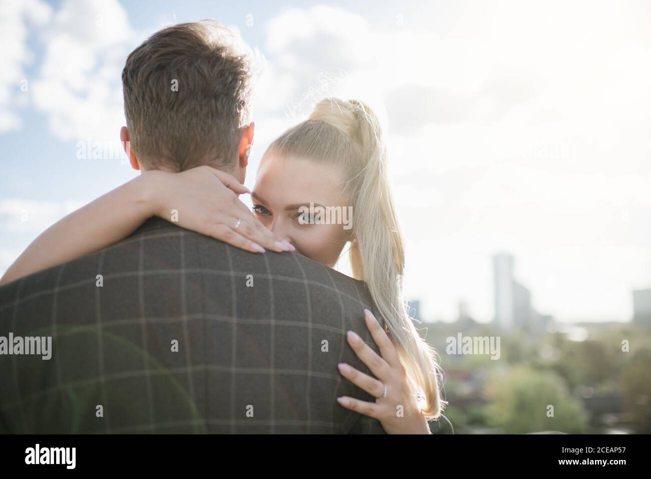 Bride holding groom with sky background Stock Photo - Alamy