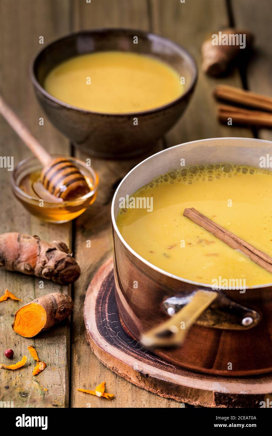 Pot full of appetizing yellow soup with honey on wooden table. Stock Photo