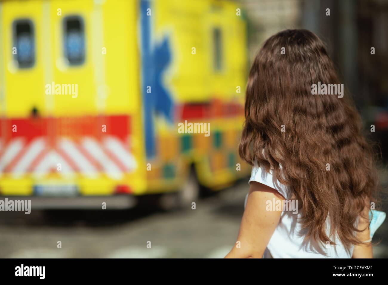 covid-19 pandemic. Seen from behind young female outdoors near ambulance. Stock Photo
