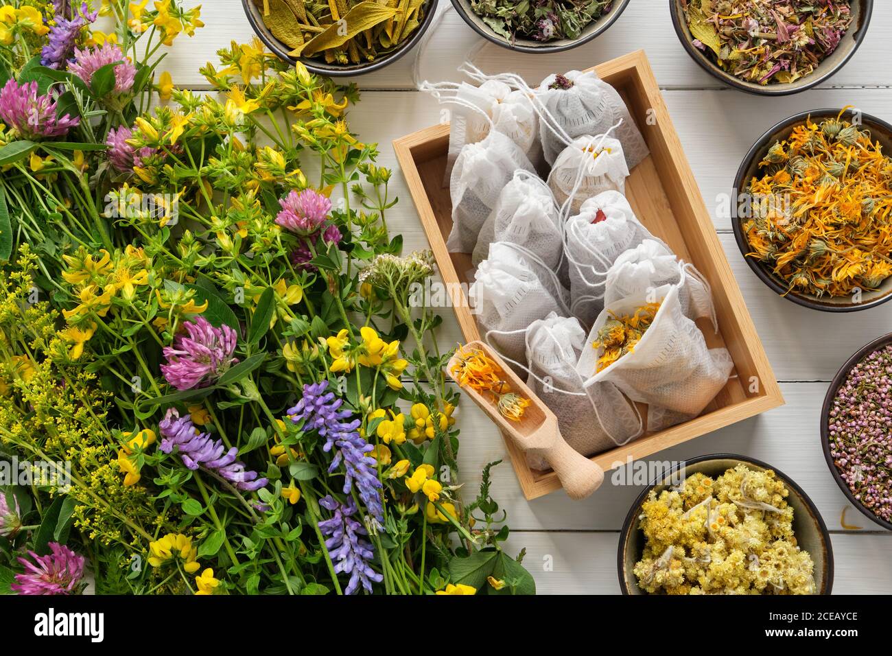 Wooden box of tea bags filled with dry medicinal herbs and bowls of dry ...