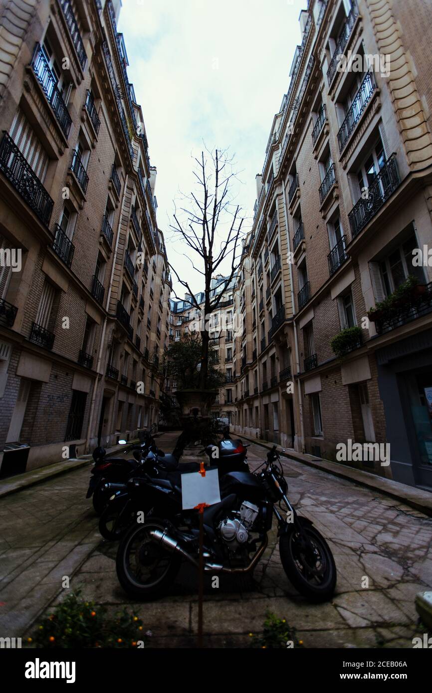 Different motorcycles parked on narrow street in Paris, France. Stock Photo