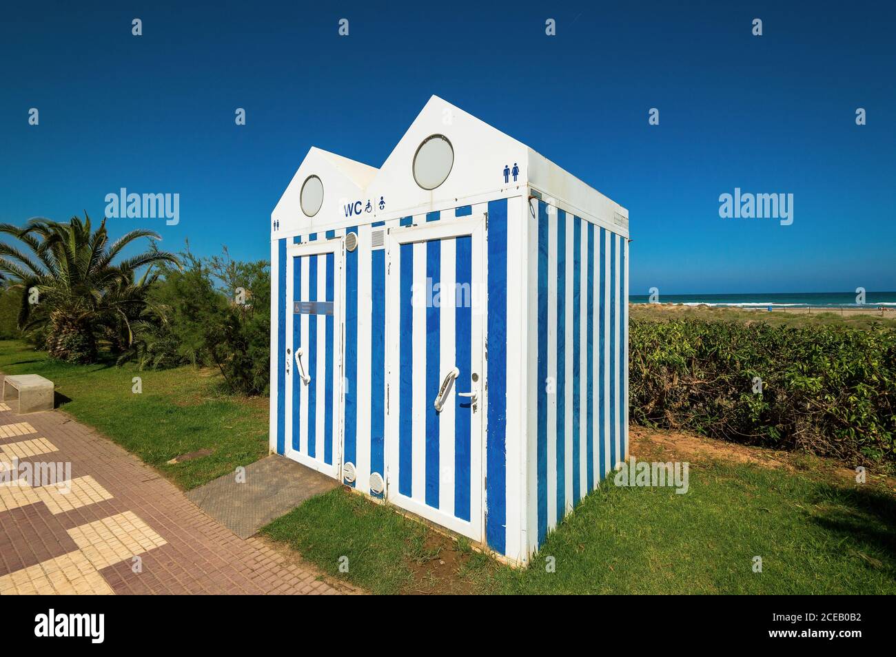 Two public lavatories standing on grass not far from beach and sea. Stock Photo
