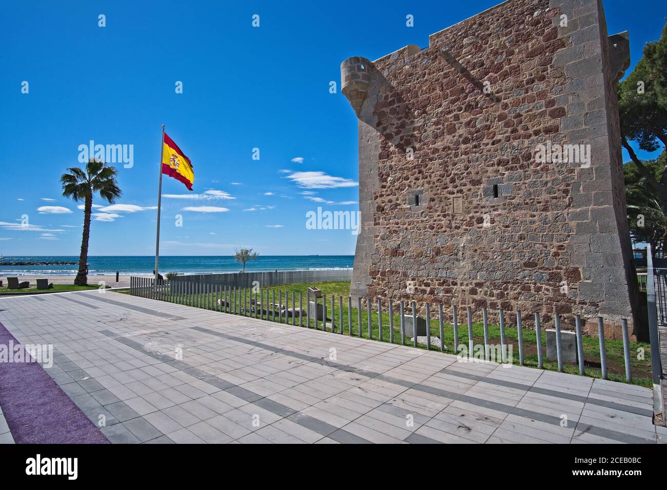 Old brick wall standing behind fence near nice beach in wonderful Spain. Stock Photo