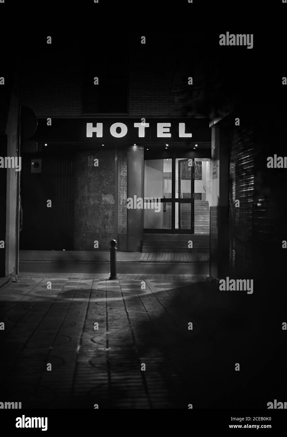 Porch and entrance glass door with burning Hotel sign above at night in black and white colors Stock Photo