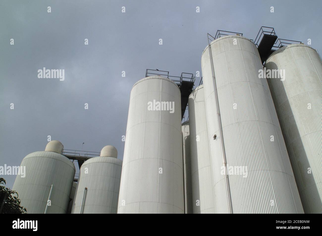 From below view of high cylinder white tanks placed outside on background of gloomy cloudy sky Stock Photo
