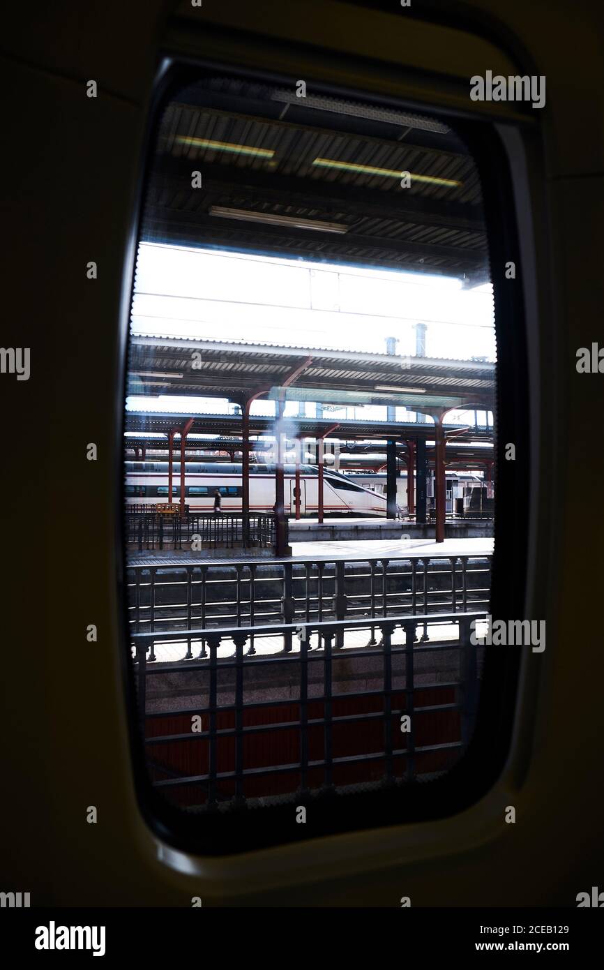 Roofed railway station with modern train arriving through window Stock Photo