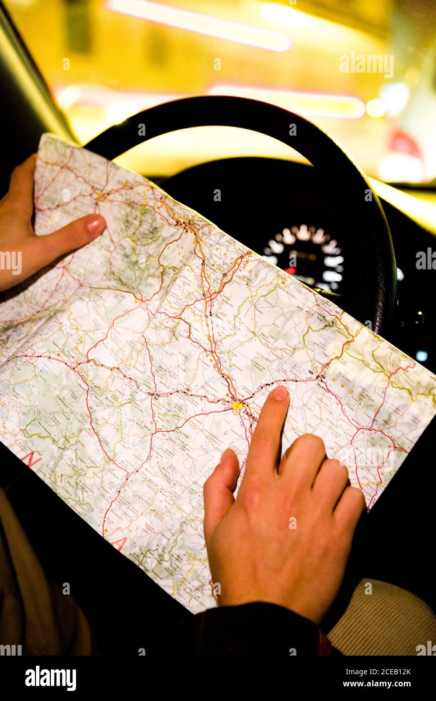 Crop shot of anonymous driver sitting in car and holding map on steering wheel pointing on location Stock Photo