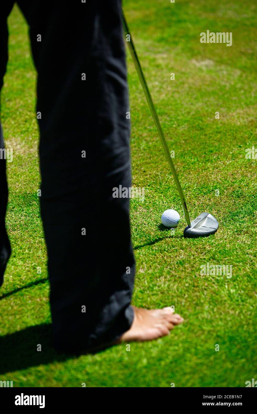 Crop back view of Man in black trousers playing golf on green lawn at daylight Stock Photo