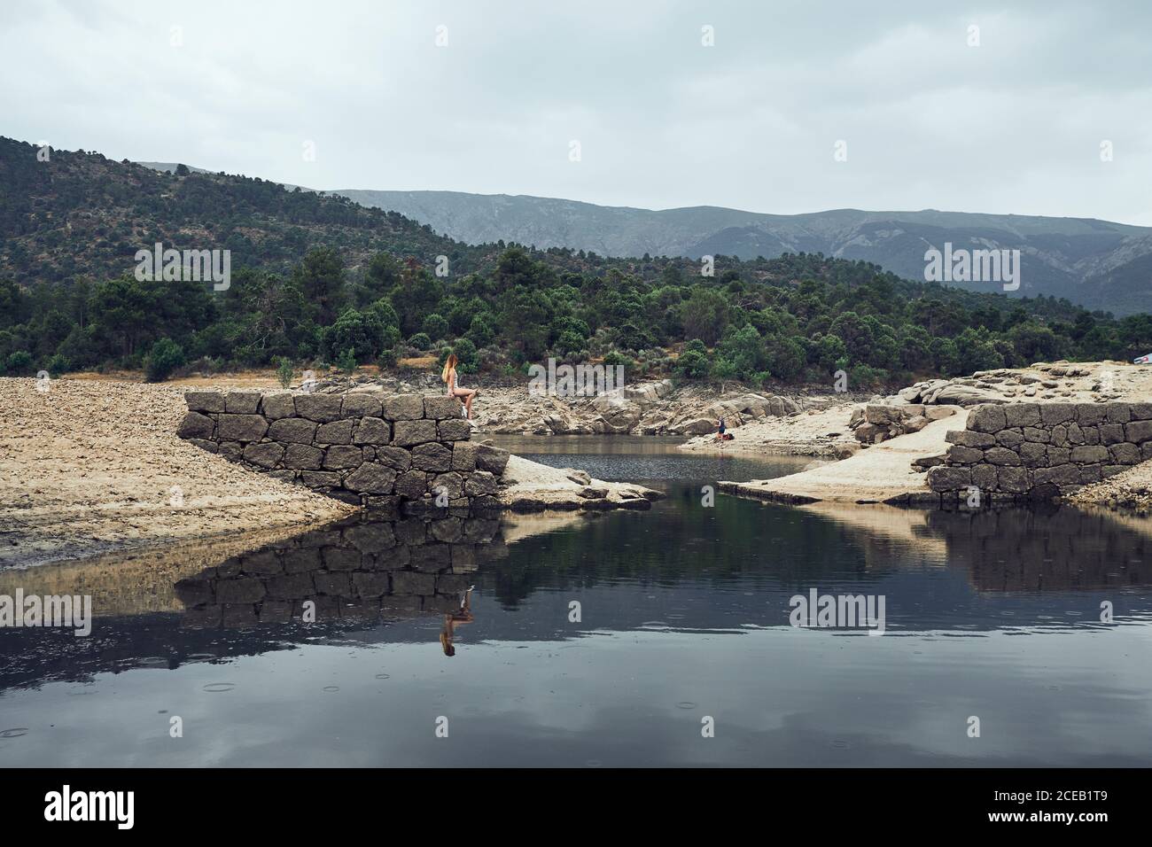 Young Woman sitting on rock near water Stock Photo