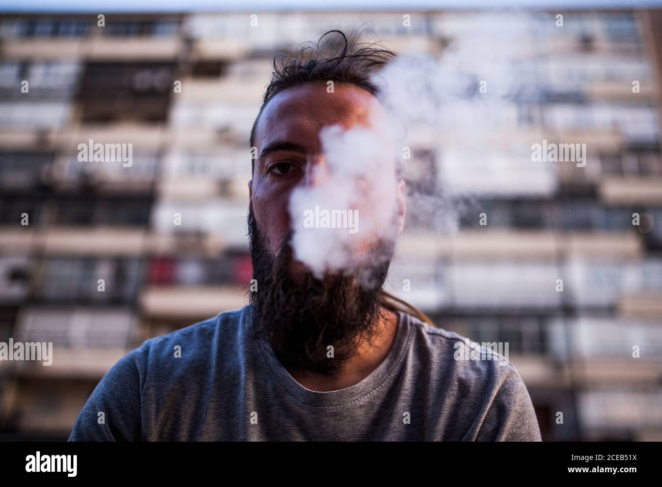 young and Caucasian Rastafarian man smoking and exposing smoke and look front Stock Photo