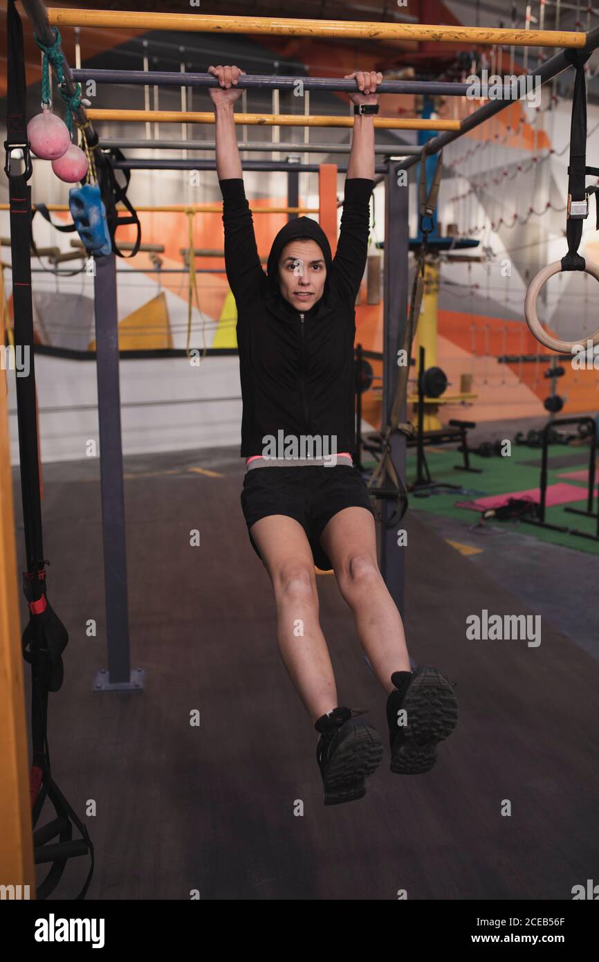 Young slim sportive lady in sportswear doing pull up exercises on ...