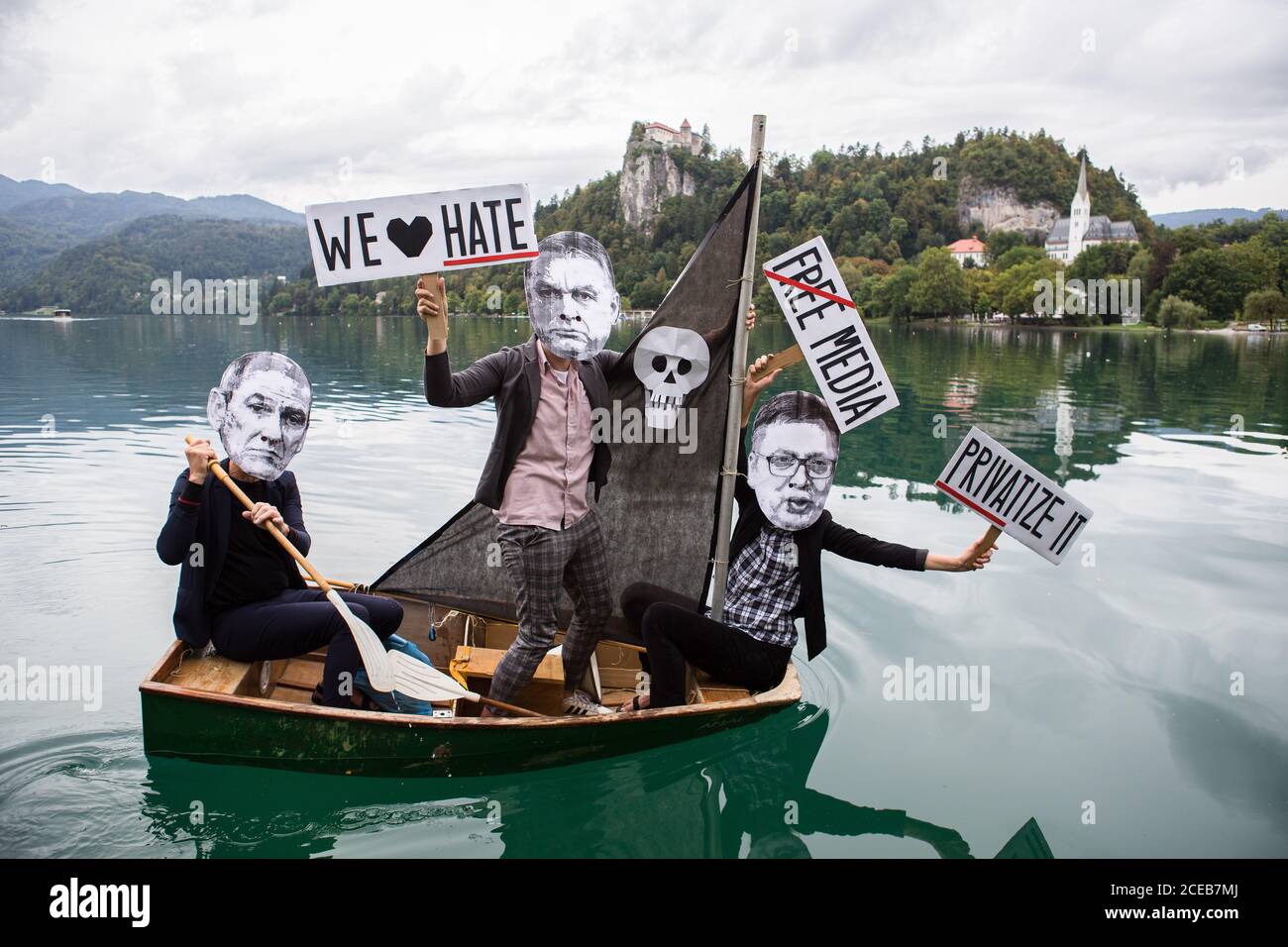 A group of protesters wearing paper masks showing the faces of Slovenian Prime Minister, Janez Jansa, Hungarian Prime Minister, Viktor Orban and Serbian president, Aleksandar Vucic row a small sailboat on Lake Bled protesting against their politics and the rise of fascism in Europe.The protest was held alongside the 15th Bled Strategic Forum where Slovenian Prime Minister Janez Jansa hosted the Hungarian Prime Minister Viktor Orban and Serbian president Aleksandar Vucic, as well as prime ministers of Czech Republic, Bulgaria, Poland, Croatia and others. Stock Photo