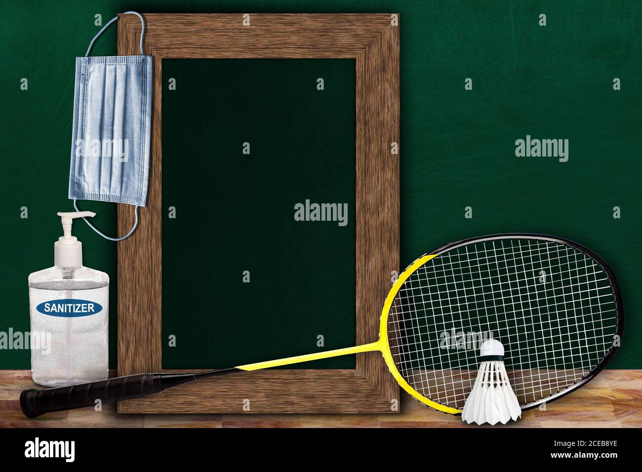 COVID-19 new normal sports concept in a classroom setting showing framed chalkboard with copy space and badminton racket and shuttlecock on wooden tab Stock Photo