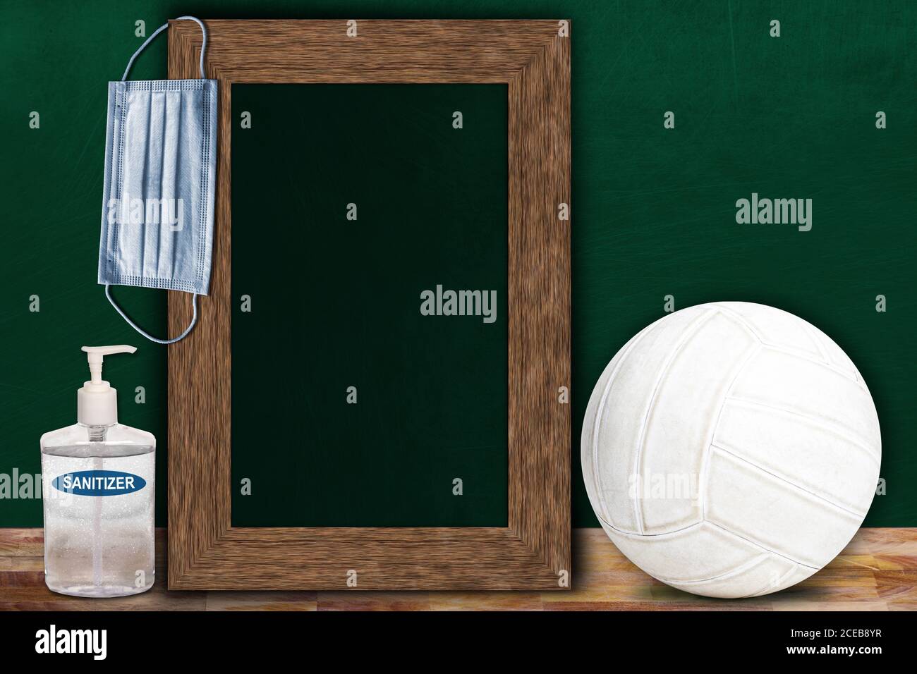 COVID-19 new normal sports concept in a classroom setting showing framed chalkboard with copy space and Volleyball on wooden table. Stock Photo