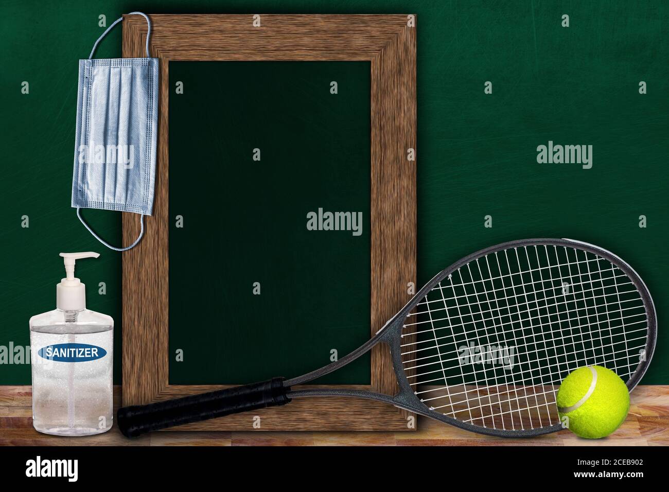 COVID-19 new normal sports concept in a classroom setting showing framed chalkboard with copy space and tennis racket and ball on wooden table. Stock Photo