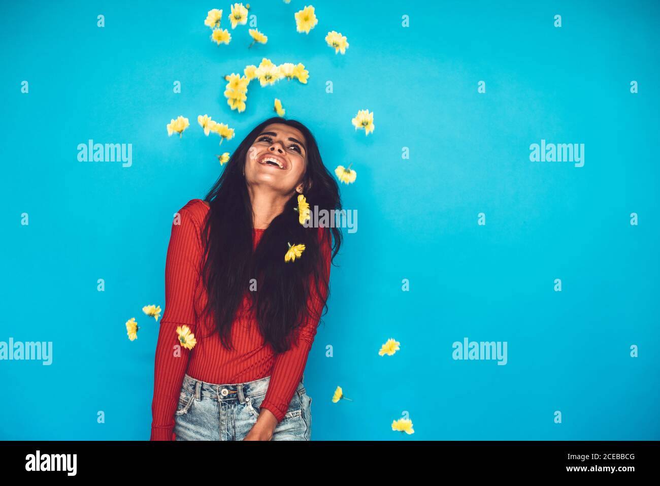 Young Woman standing in studio and throwing flowers Stock Photo