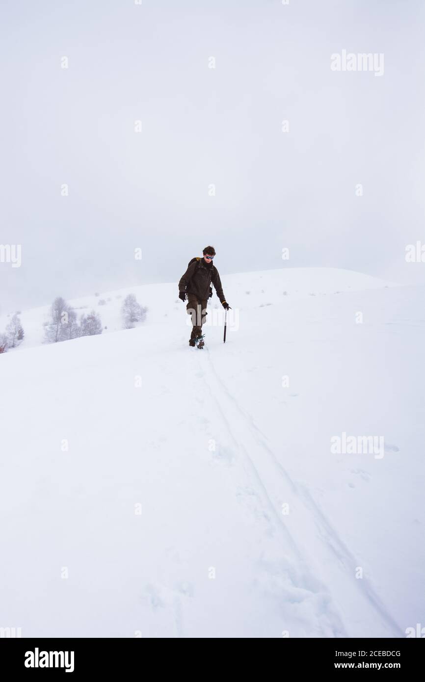 Tourist walking up on snowy mountain Stock Photo