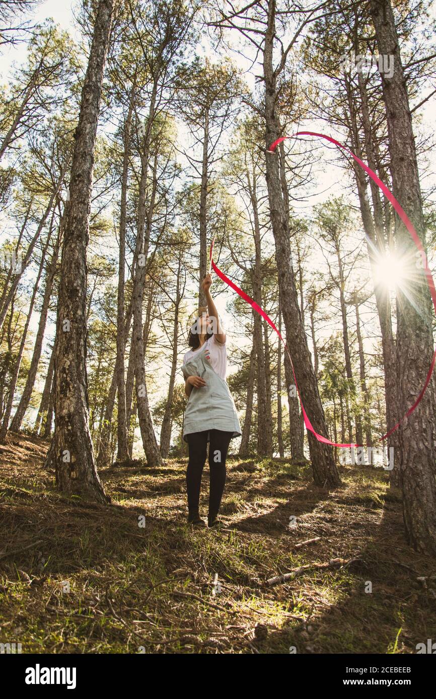 Young Woman waving with bright wand in sunny forest in backlit Stock Photo