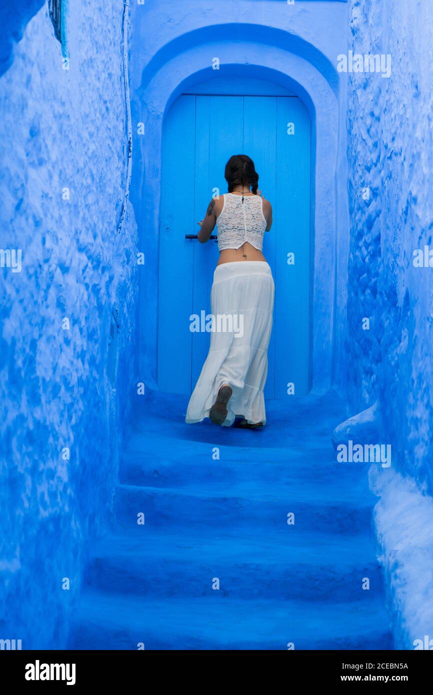 Young Woman opening blue door Stock Photo