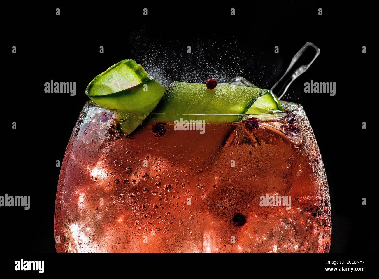 closeup of bubbly red gin tonic with cucumber and pepper Stock Photo