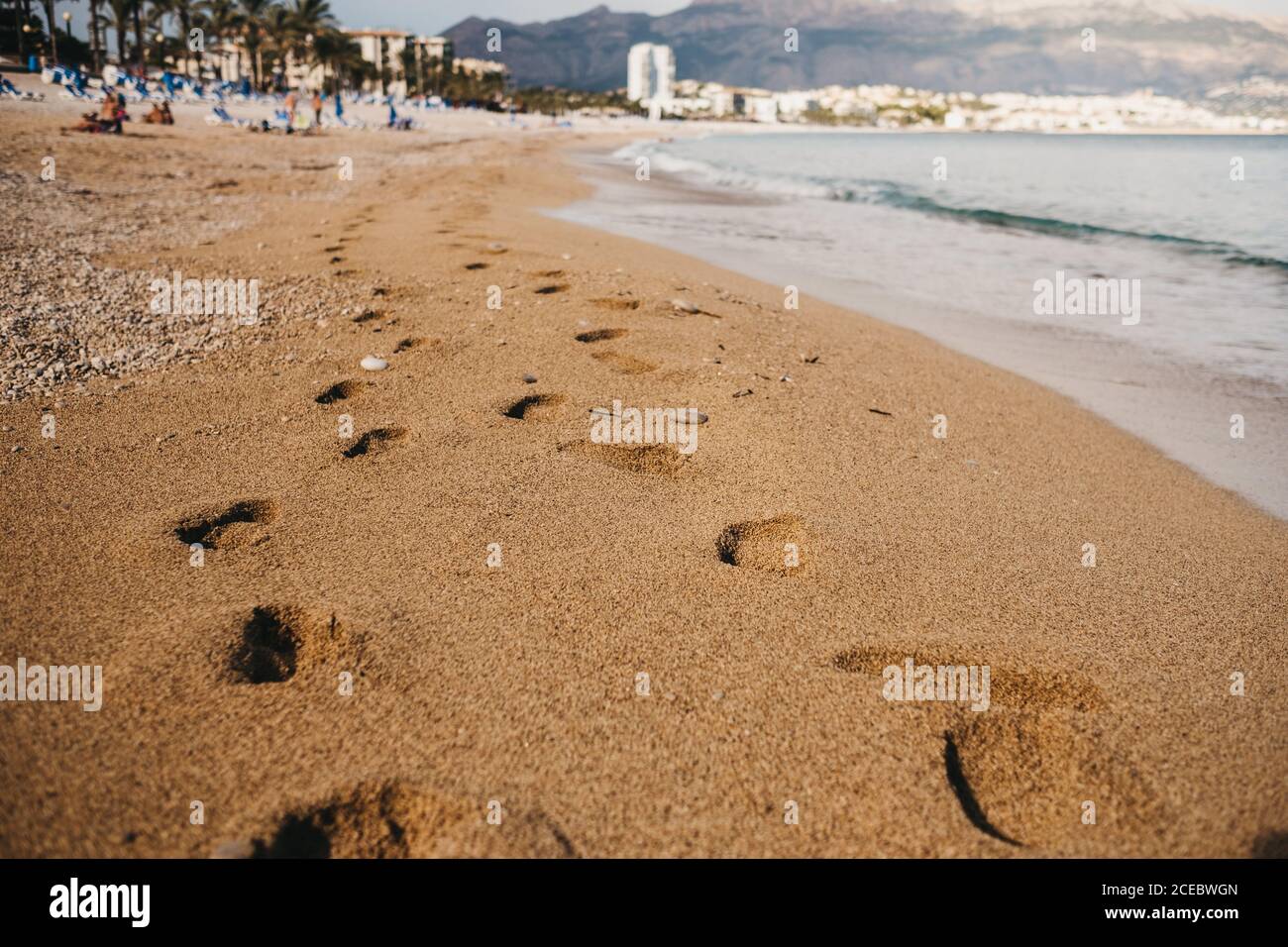 Traces of human feet on wet sand near waving sea in Altea, Spain Stock Photo