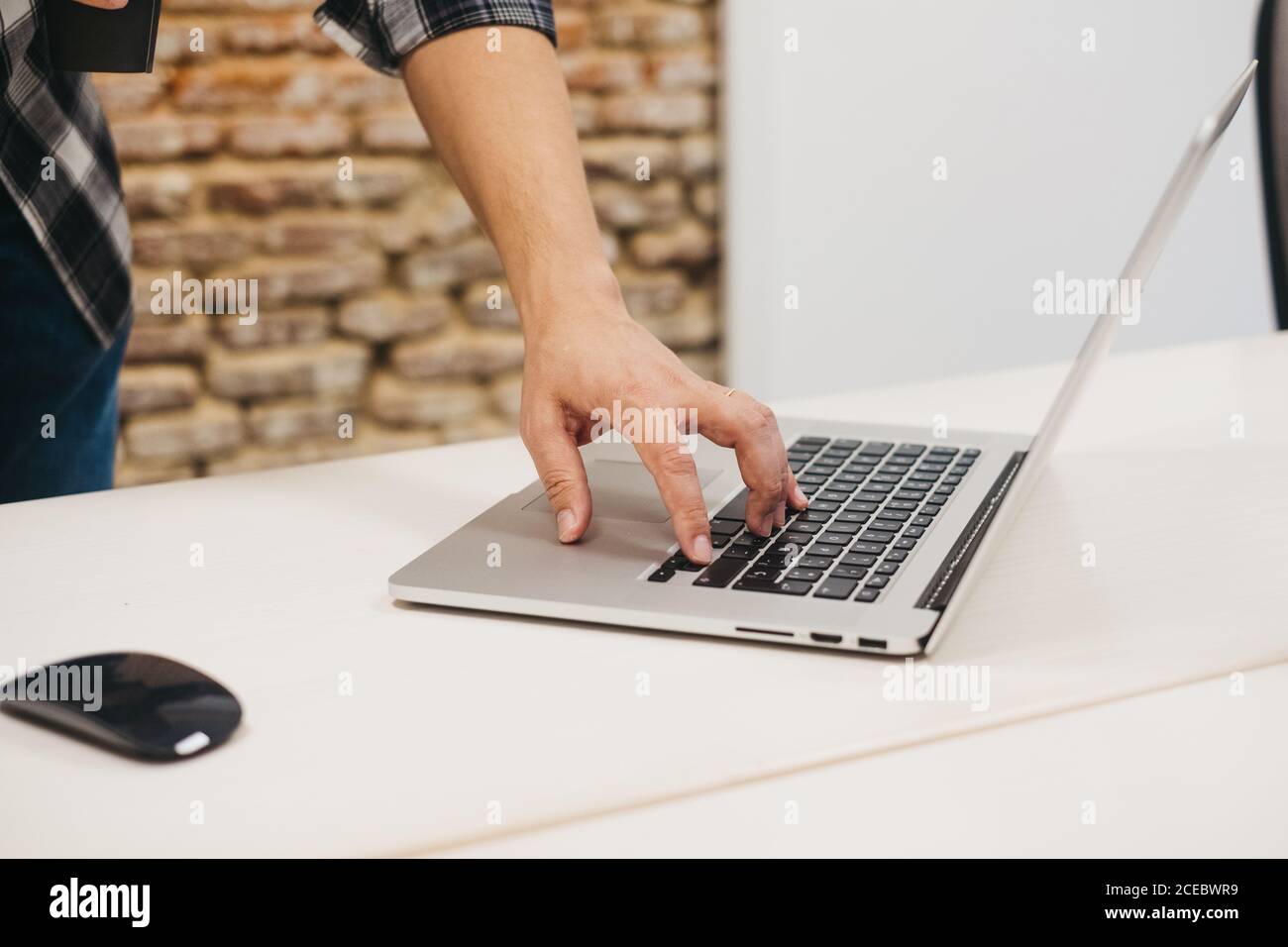 man typing on laptop at table near computer mouse Stock Photo