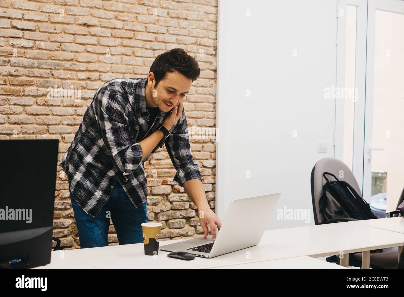 Young man with cup talking on smartphone Stock Photo