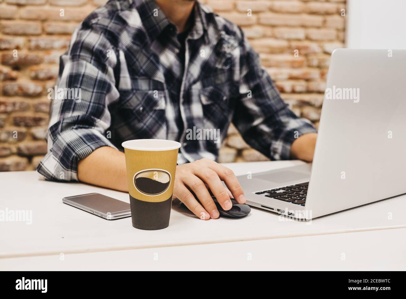 Young man using laptop at table with cup and smartphone Stock Photo