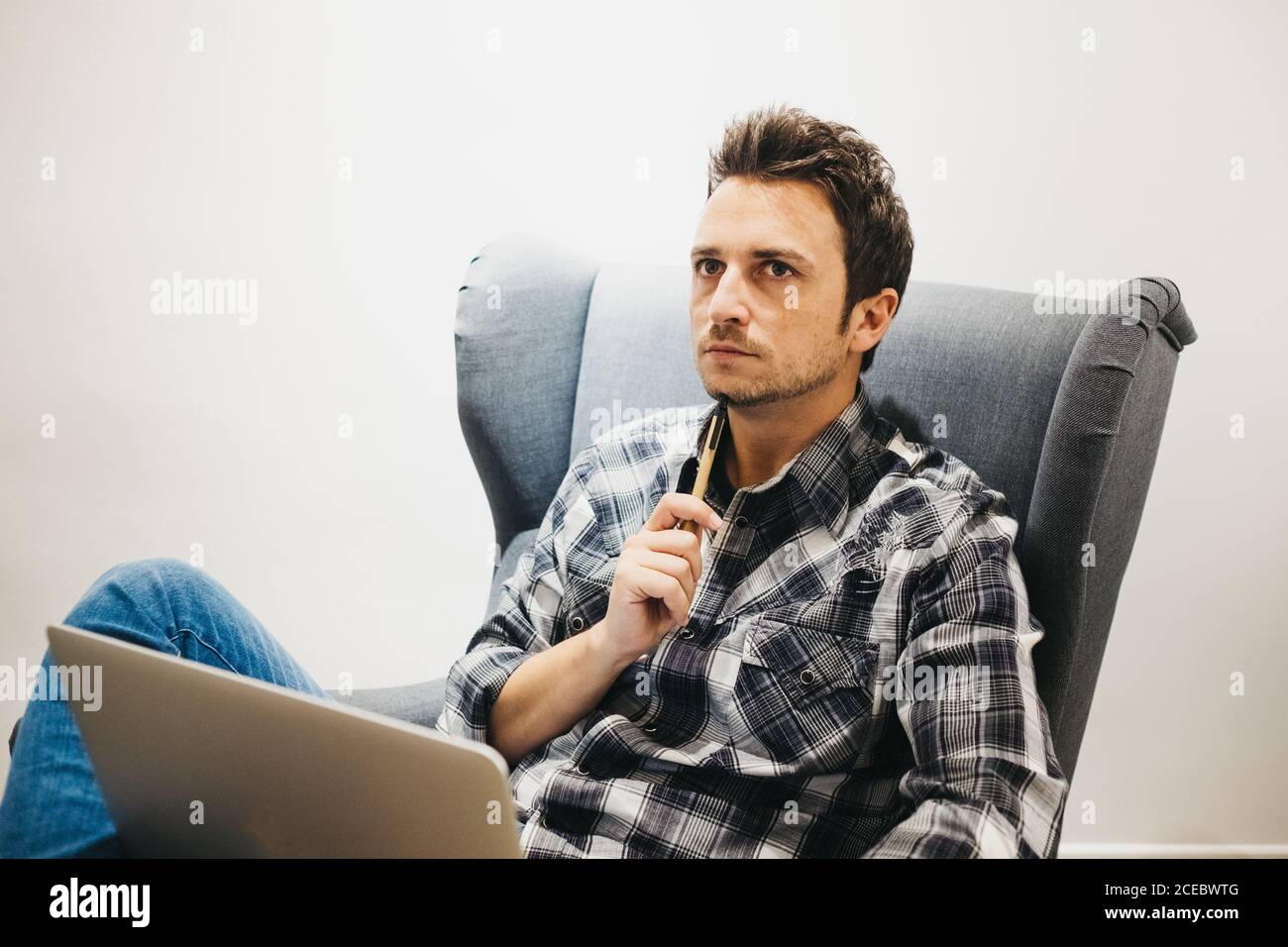 Young man using laptop on armchair Stock Photo