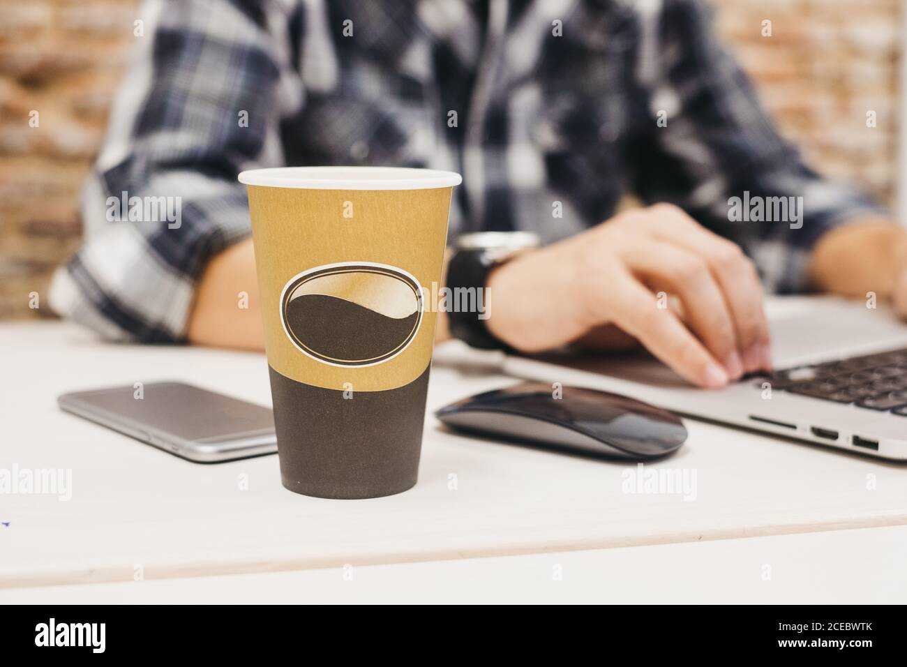 Young man using laptop at table with cup and smartphone Stock Photo