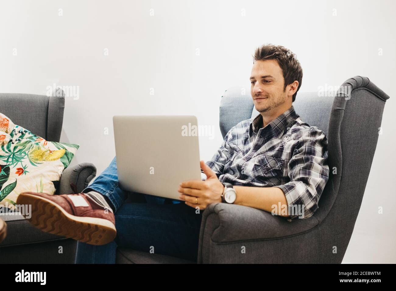 Young man using laptop on armchair Stock Photo