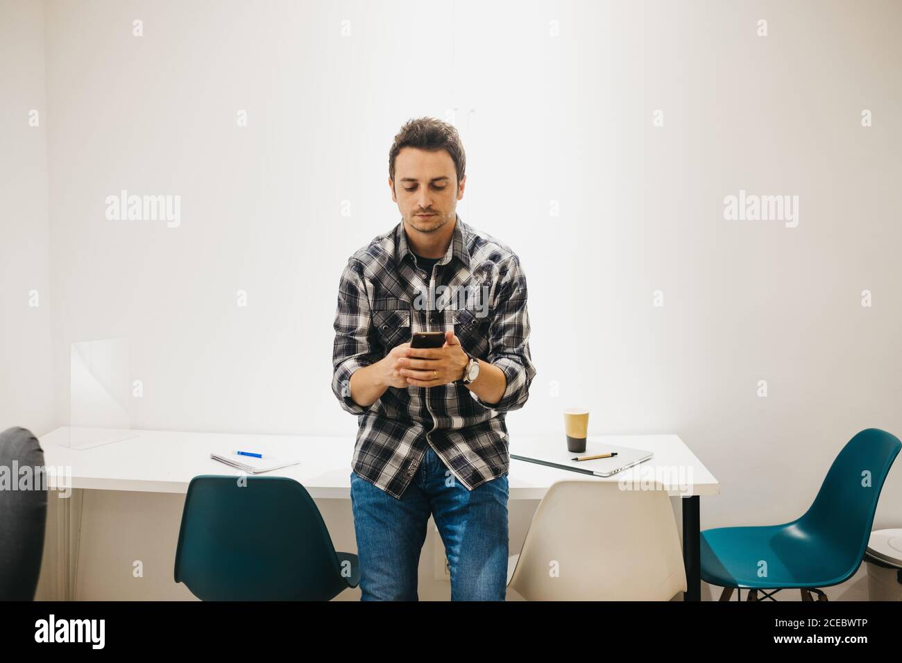 Young man with laptop talking on smartphone Stock Photo