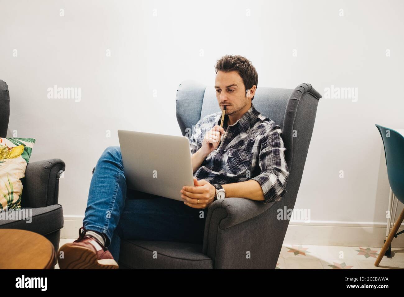 Young man using laptop on armchair Stock Photo