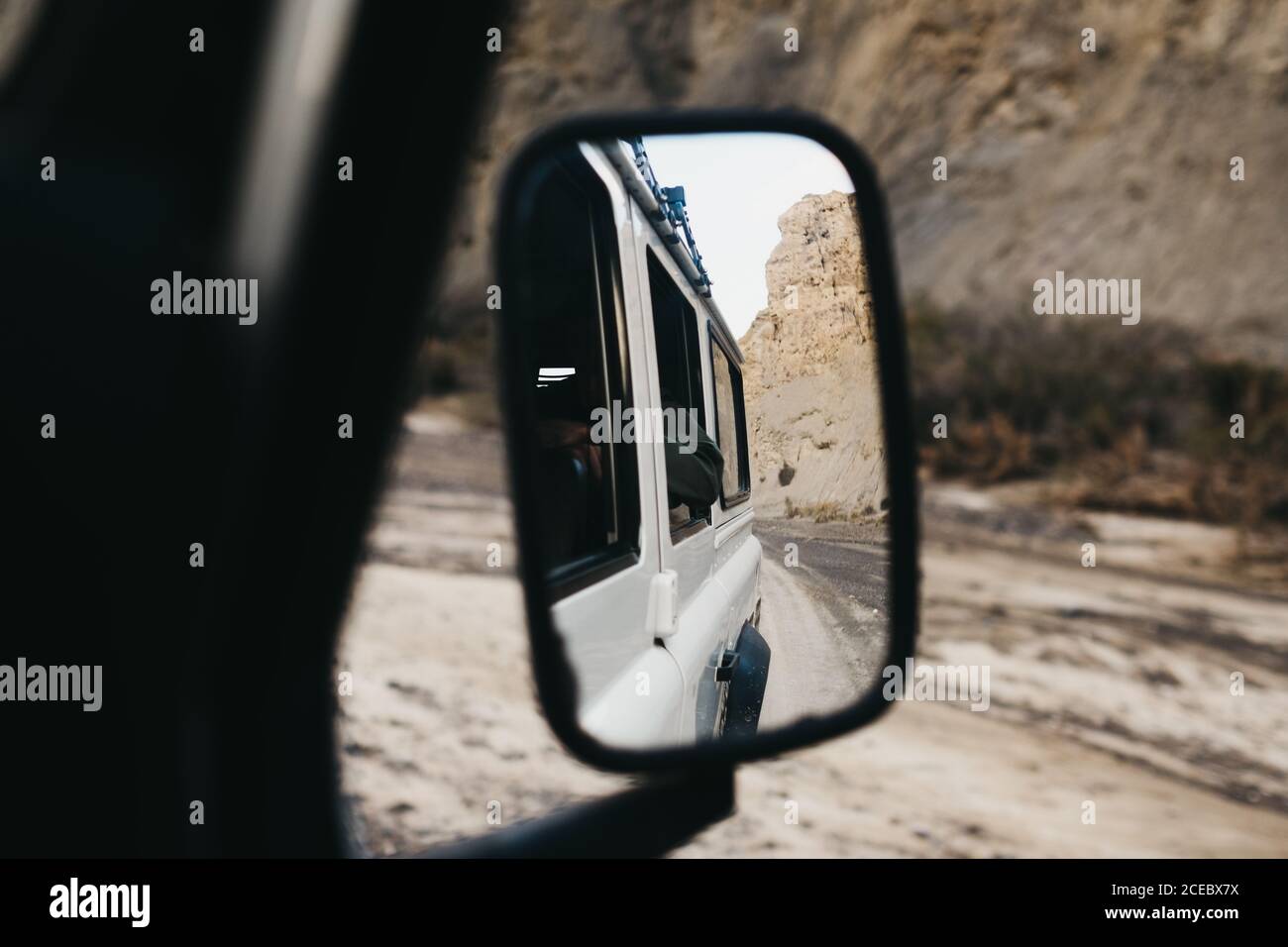 Shot of side mirror of car with reflection of canyon rocky roadway and