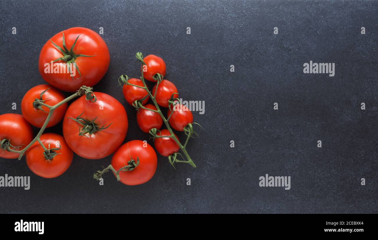 Different organic tomato varieties on a dark stone kitchen table with space for text or image Stock Photo