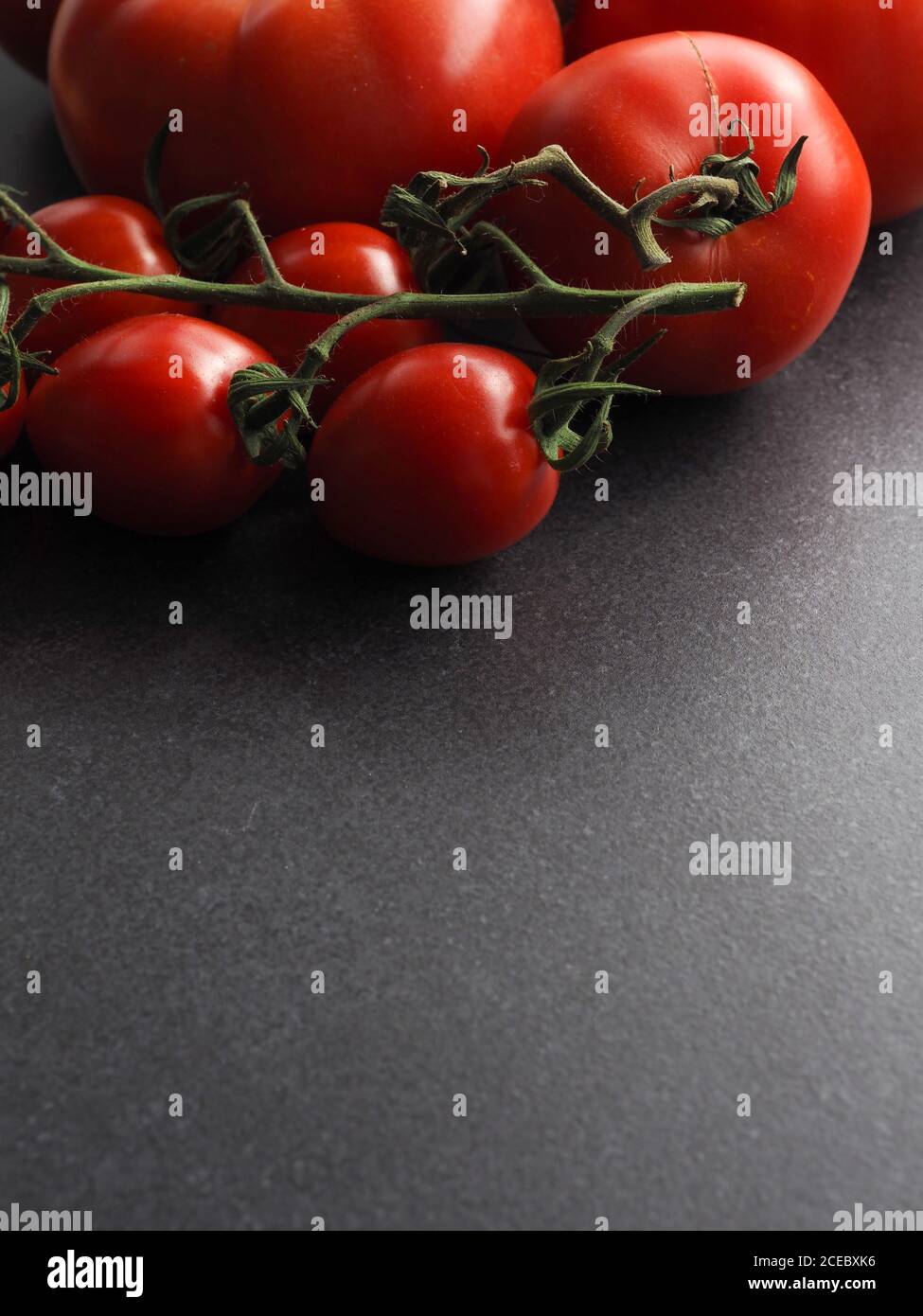 Different organic tomato varieties on a dark stone kitchen table with space for text or image Stock Photo