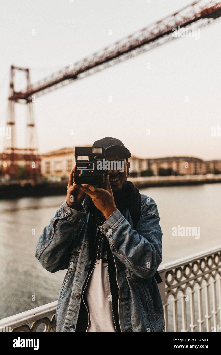 Cheerful man with camera on embankment Stock Photo