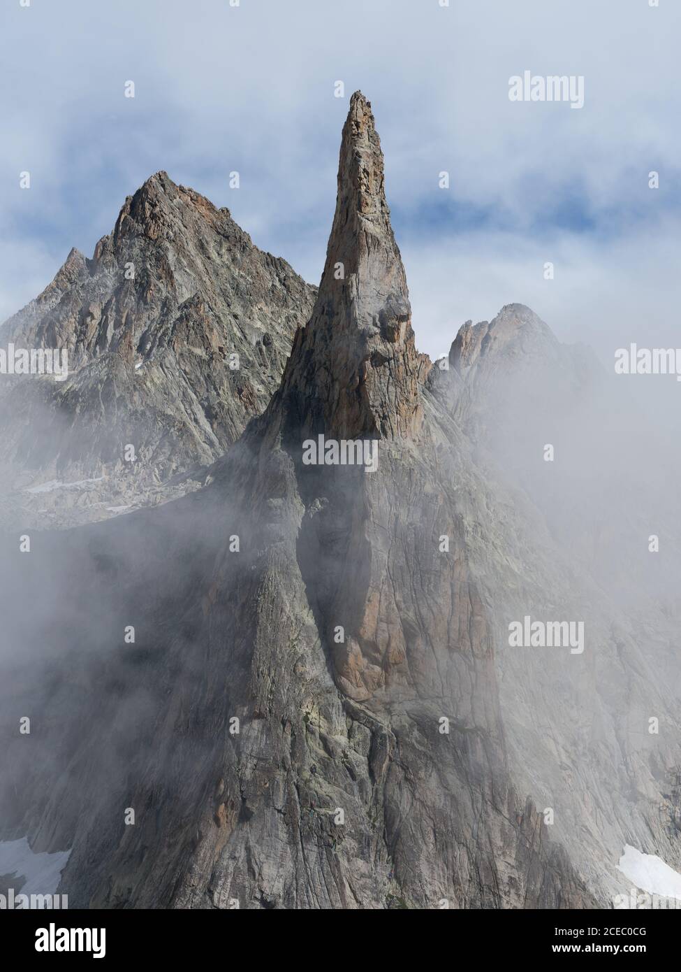 AERIAL VIEW. Towering granite peak in the fog. Aiguille de Dibona, Saint-Christophe-en-Oisans, Isère, Auvergne-Rhône-Alpes, France. Stock Photo