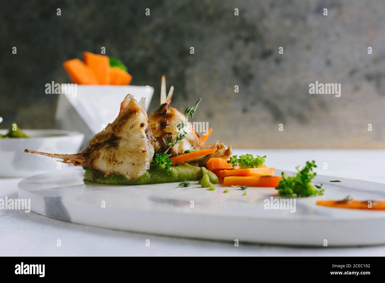 Scorpion Fish Cook grilled scorpion fish with mashed peas and carrot sticks, on a marble ...