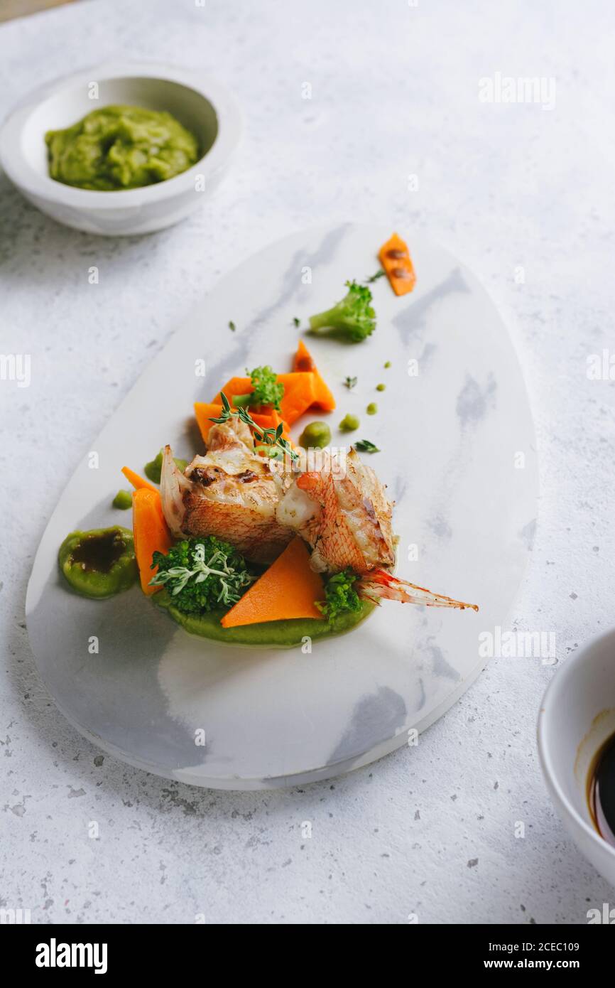 Scorpion Fish Cook grilled scorpion fish with mashed peas and carrot sticks, on a marble ...