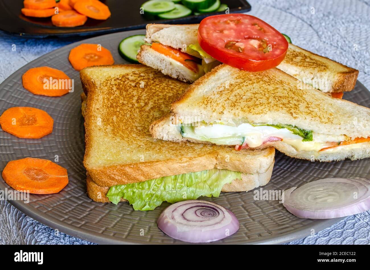 Toasted Vegetable Cheese Sandwiches decorated with sliced tomatoes, carrots and onions Stock Photo