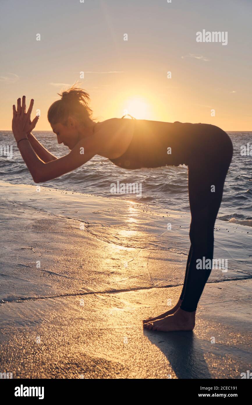 Slim female in sportswear bending aside while practicing yoga near sofa at  home Stock Photo - Alamy