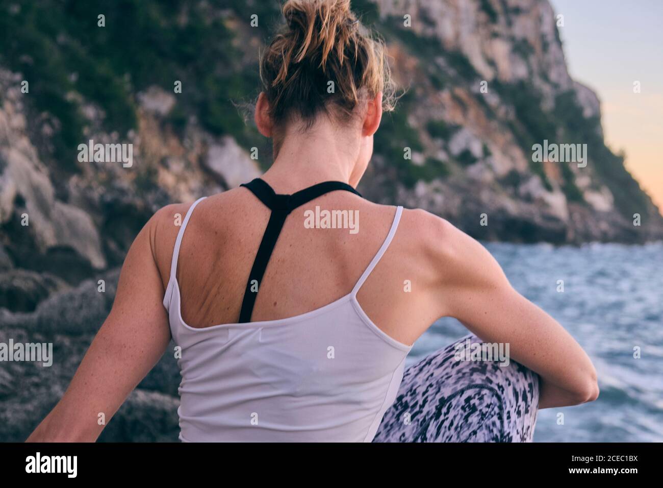 anonymous female twisting body on rock near sea Stock Photo - Alamy