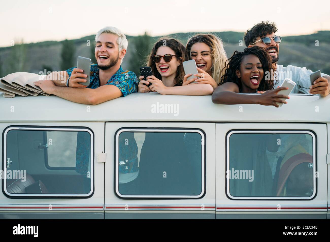 Friends using smartphones in van Stock Photo