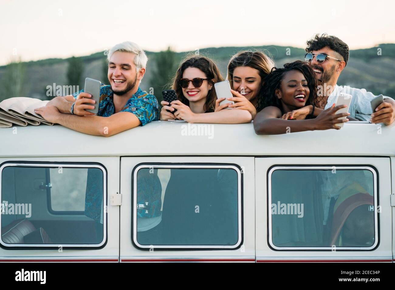 Friends using smartphones in van Stock Photo